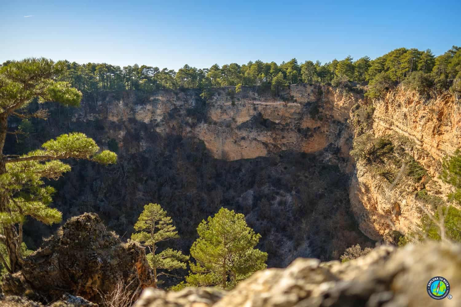 Interior de una gran torca rodeada de pinares